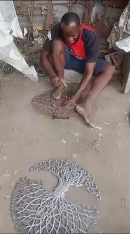 Hammer and chisel cutting steel barrel to make a tree of life wall decor